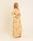 Noor champagne feather-print dress, three-quarter view showing the shirred waist