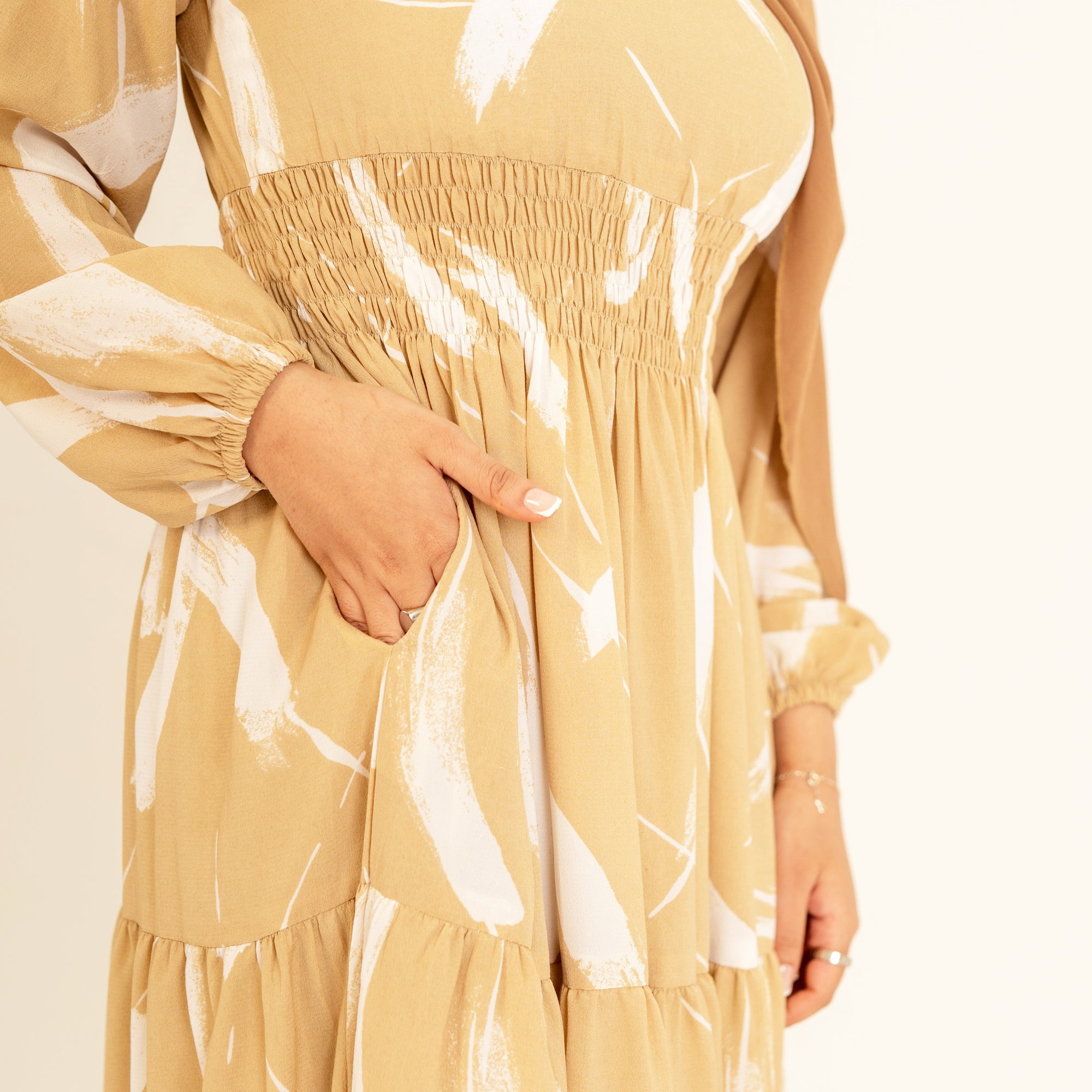 Noor champagne feather-print dress, close view of the shirred waist and tiered skirt